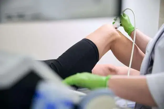 Clinician performing an ultrasound assessment of a patient's knee